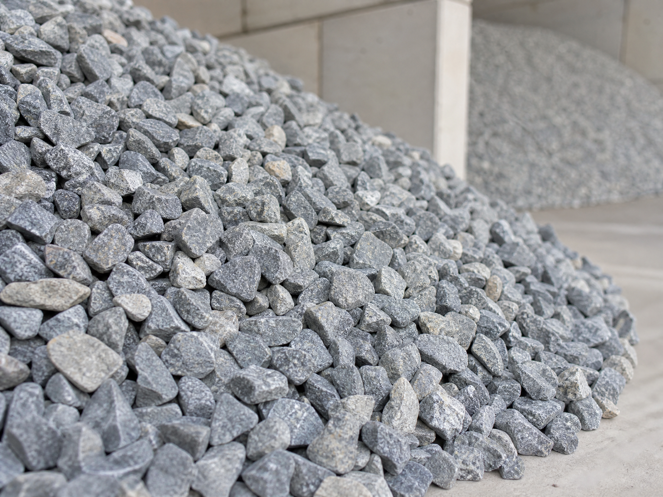 Piles of crushed gravel and construction aggregate on a dark industrial site