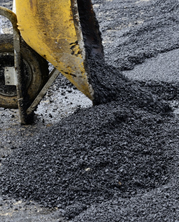 Construction site with heavy machinery and trucks on a dusty road, dim industrial light